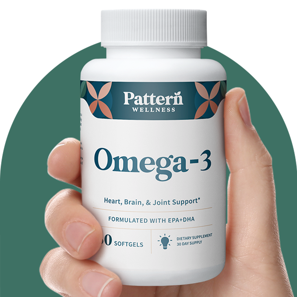 A hand holding a bottle of Pattern Wellness Omega-3.