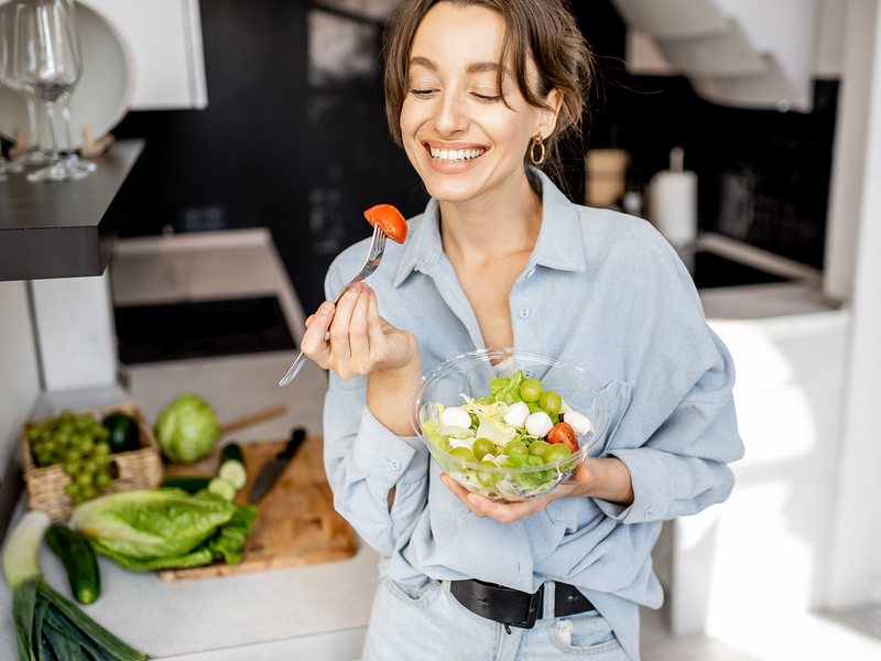 A woman eating fresh vegetable salad.