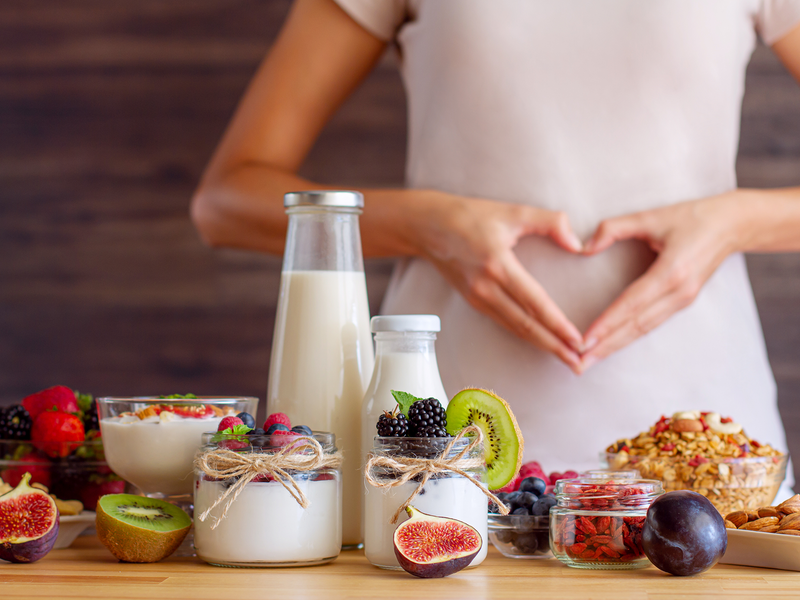 A woman forms a heart shape with her hands and has an assortment of delicious foods.