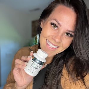 A female customer with a bright smile holding a bottle of Pattern Wellness Organic Garlic.