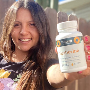 A female customer smiling while holding a bottle of Pattern Wellness Berberine.