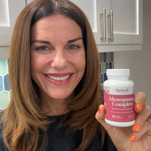 A female customer smiling while holding a bottle of Pattern Wellness Menopause Complex.