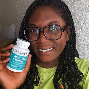 A female customer with a bright smile holding a bottle of Pattern Wellness Vitamin B Complex.