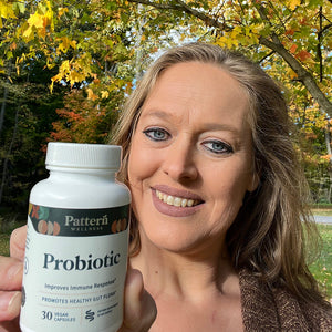 A female customer smiling while holding a bottle of Pattern Wellness Probiotic.