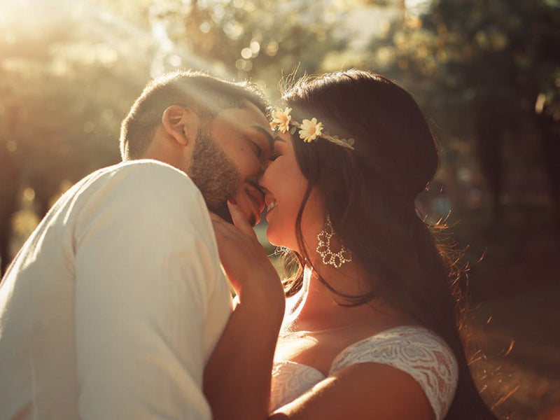 A man and woman share a romantic kiss under the warm sunlight.