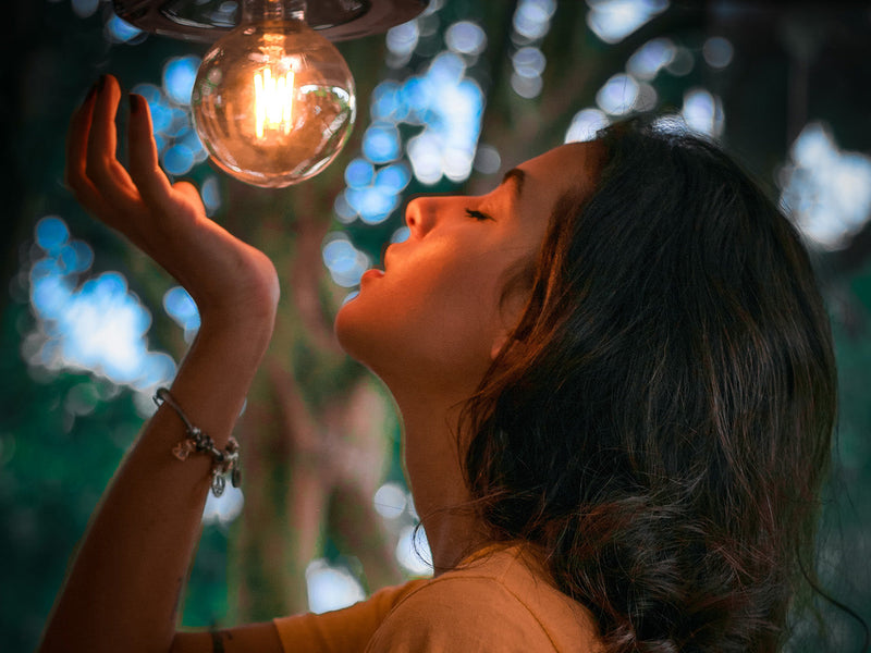 A woman is about to hold a glowing light bulb.