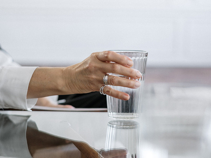 A person holding a clear glass of water.