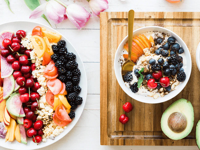 Two plates filled with a colorful assortment of fresh fruits and vegetables.