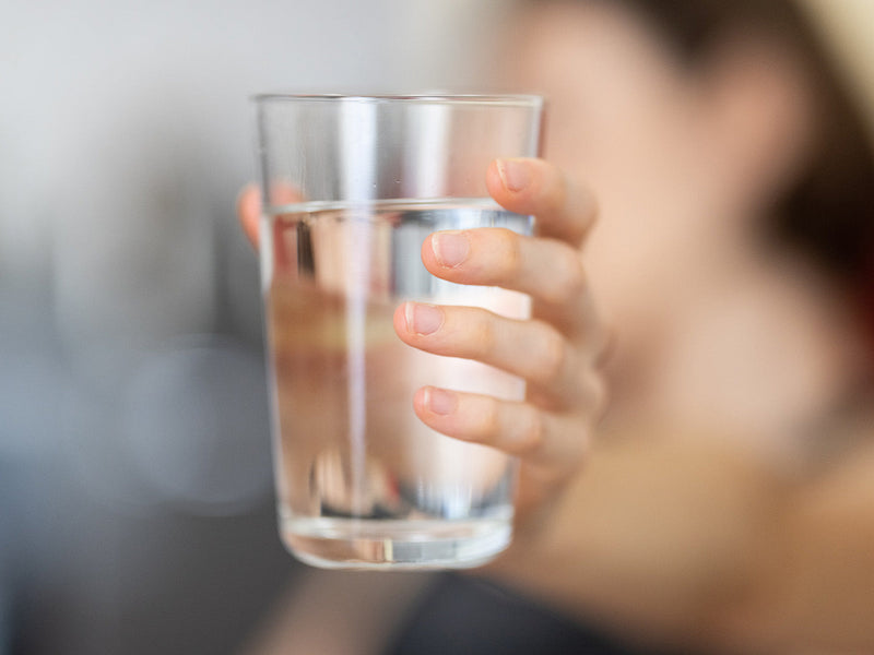 A person is holding a clear glass of water.